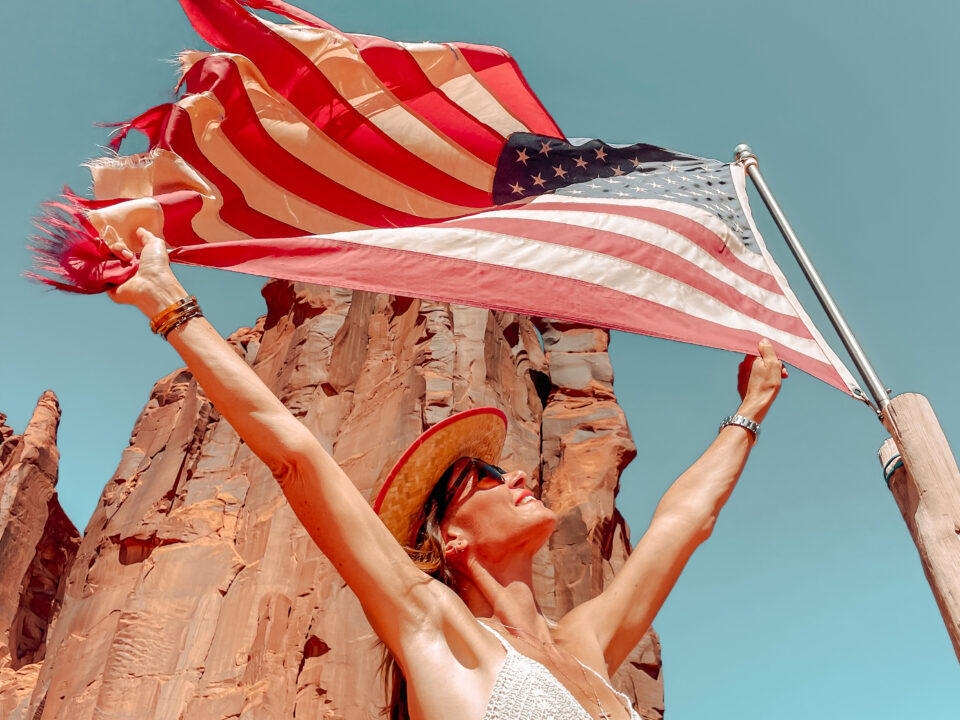 Sabrina brandissant un drapeau américain dans le désert, symbole de sa LLC américaine d'entrepreneuse expatriée